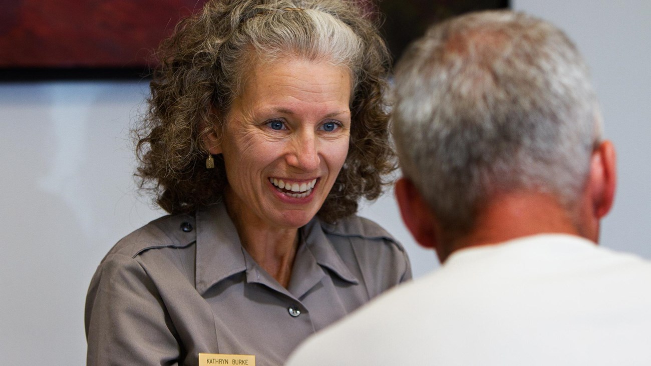 a smiling female ranger greets a male visitor