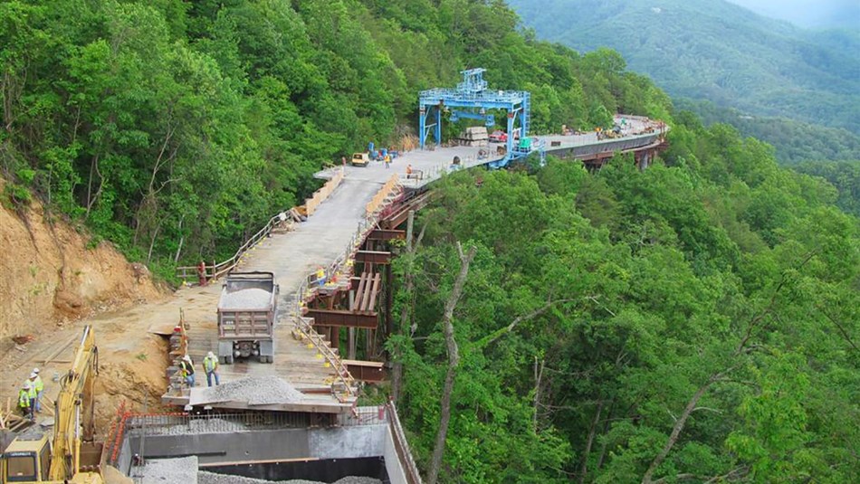 a big construction project on the road on the side of a wooded mountain