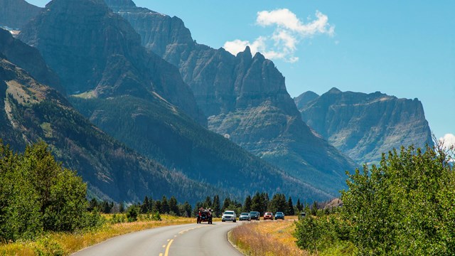 mountain on left in background, road in center with cars driving toward you