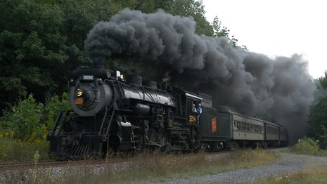 an old black locomotive, smoke coming out of the top