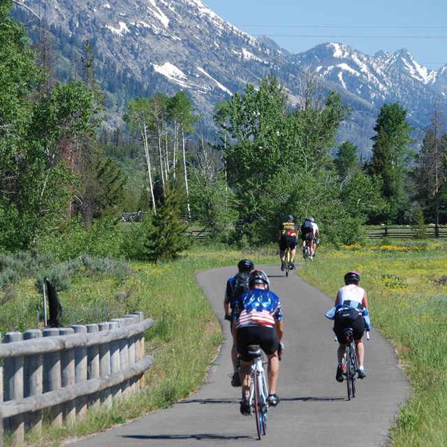 Riding bikes on paved path with the Grnad Teton mountains in the back
