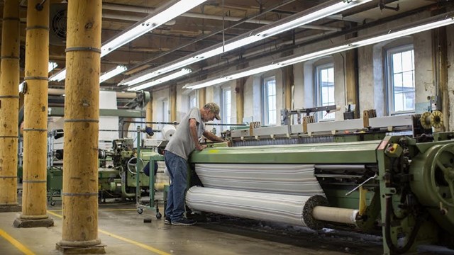 man checking a loom in the woolen mill