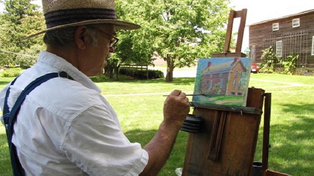 man painting outside of the amana arts guild