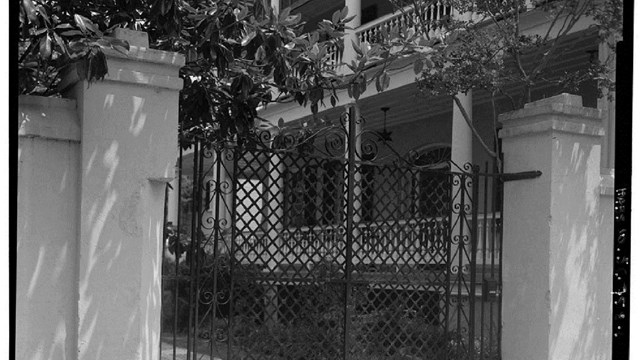 Black and white picture of a gate in front of a house