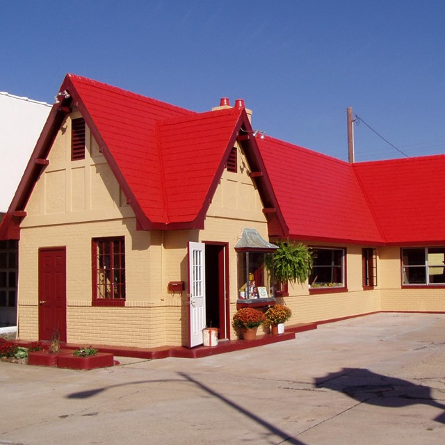 A small wood house with a bright red roof.