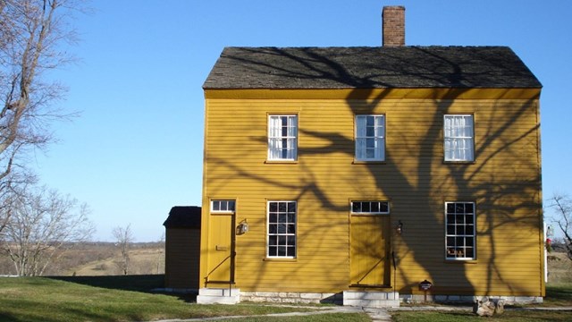 yellow clapboard structure with two doors