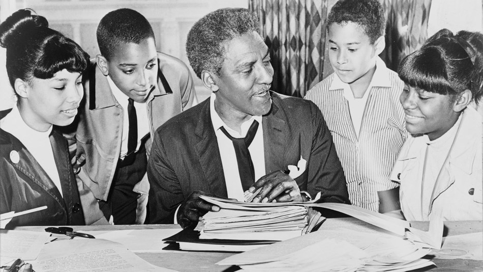 Photo of a seated man surrounded by children. Library of Congress.