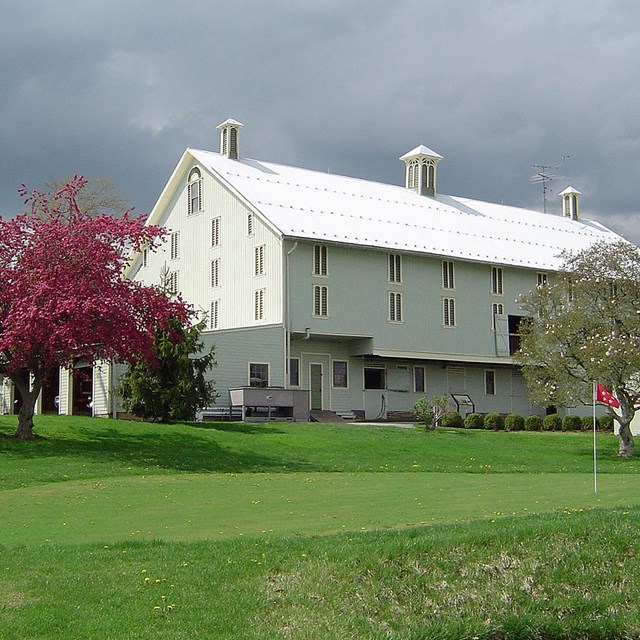 Gray sky with large farm building and putting green. NPS photo. 