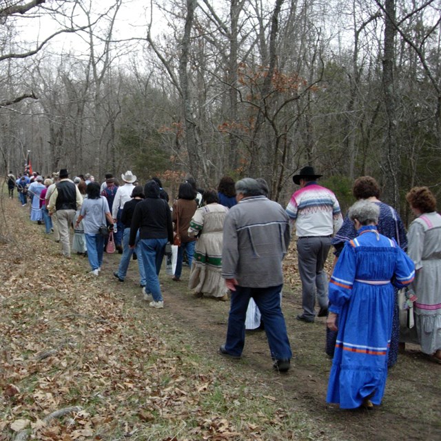 People walking on a path through the woods. NPS photo. 