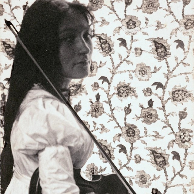 Woman sitting holding a violin. 