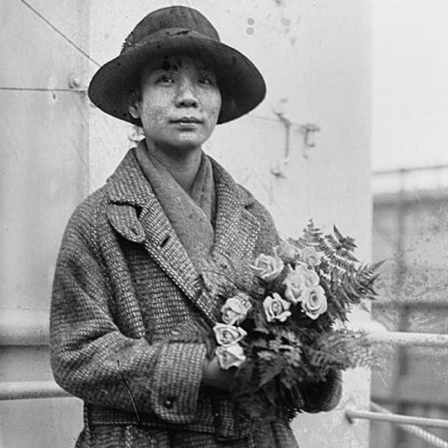 Woman standing, holding flowers. 