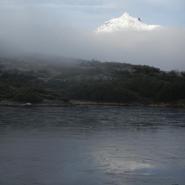 Frozen lake with white peak of a mountain in the background. Courtesy NPS. 