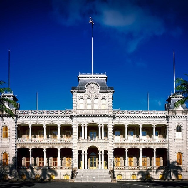 Exterior of stone palace with palm trees. Public Domain 