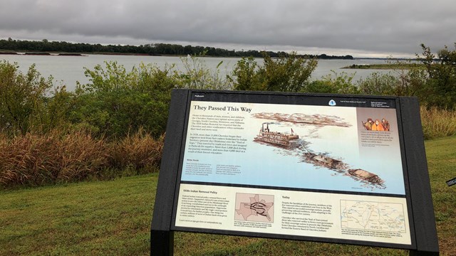 A few wayside signs sit on a cement river overlook.