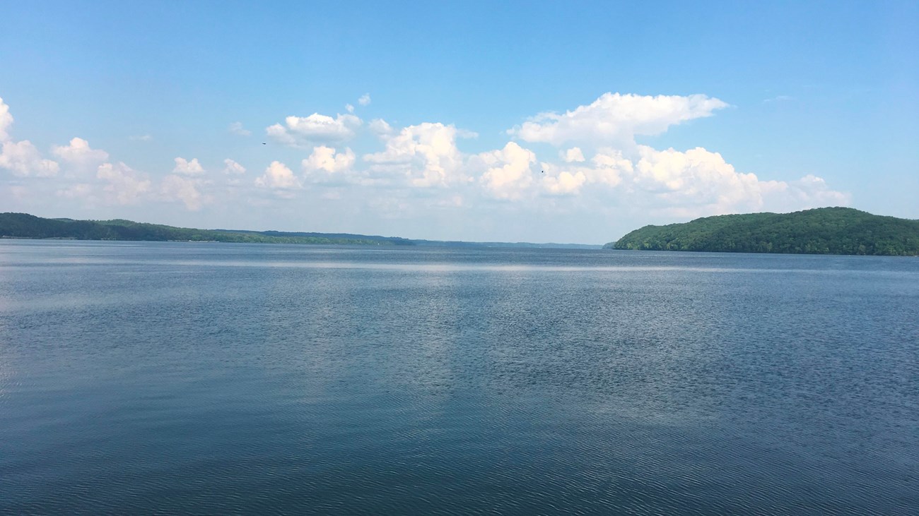 A large, flat lake under blue sky and clouds.
