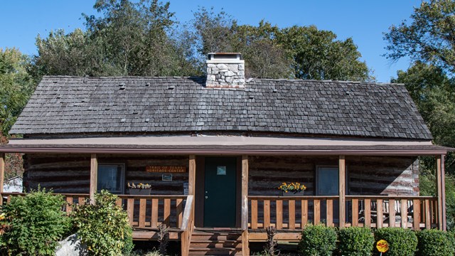 A small log cabin with a large covered front porch.