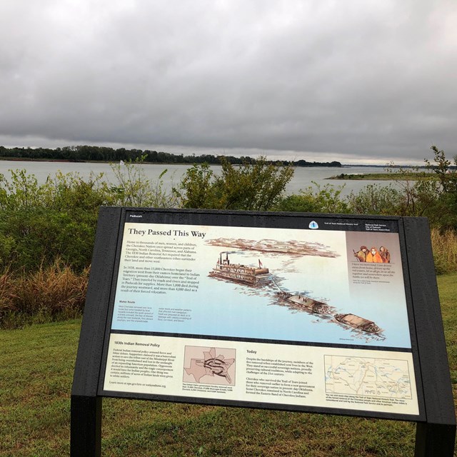 A few wayside signs sit on a cement river overlook.