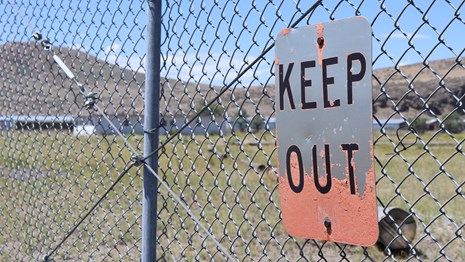 Keep Out sign with the jail behind the fence