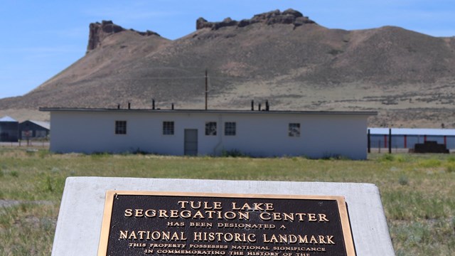 white concrete building with distinctive rock formation in background