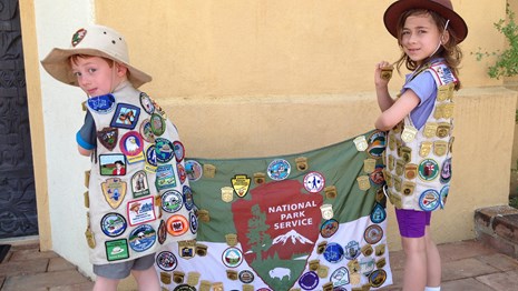 two children with vests full of junior ranger badges