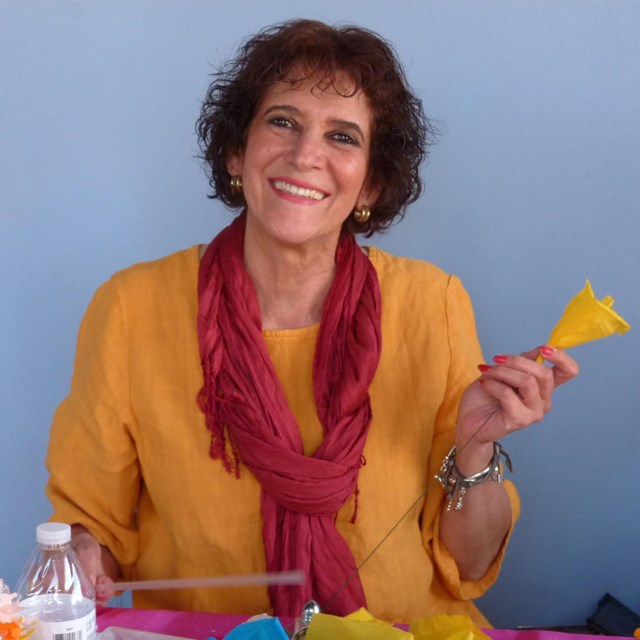 woman holding paper flower, smiling