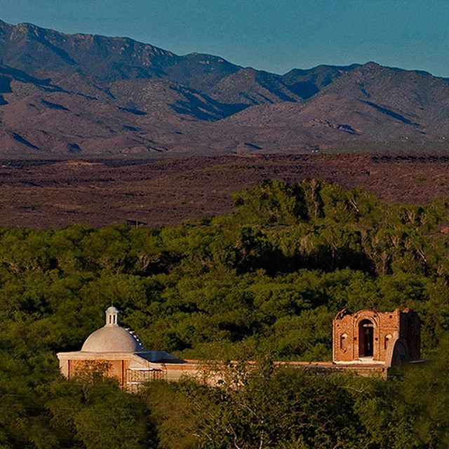 Landscape view of adobe church with mountains at sunset.