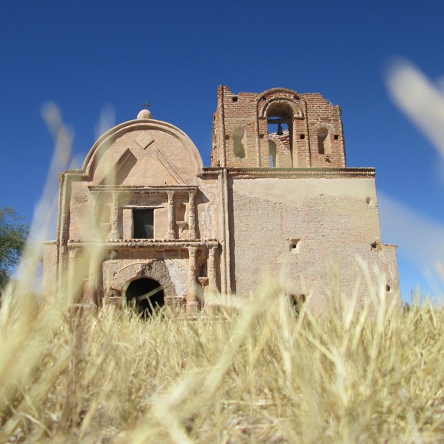 Image from dry grass looking up to adobe church.