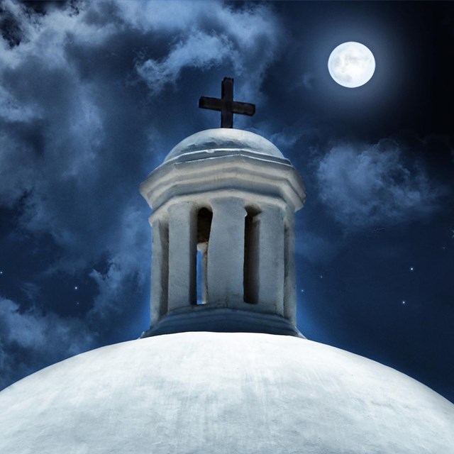 White dome with cloudy night skies and moon behind it.