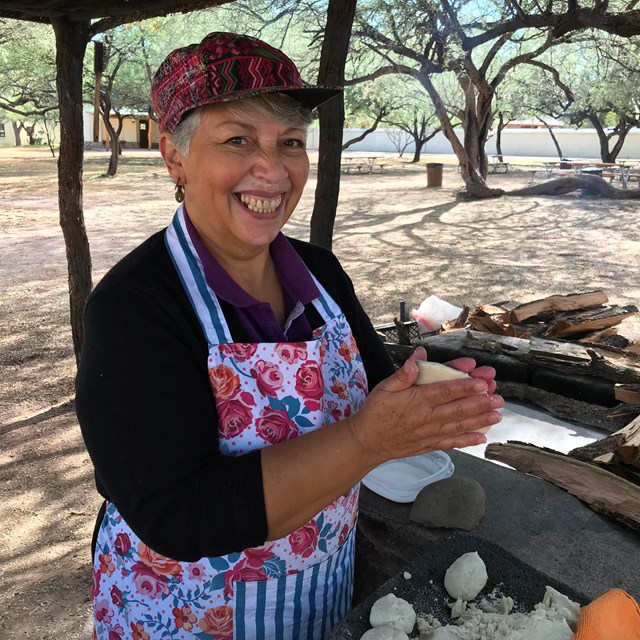 woman at outdoor kitchen making tortillas