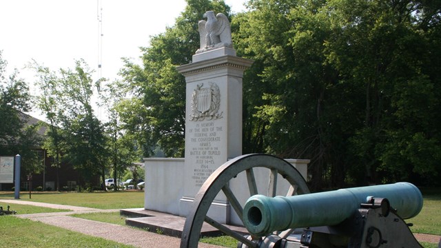White granite monument with carved bald eagle at the top flanked by two civil war cannons