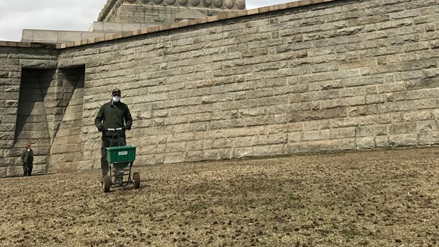 man with fertilizer in front of statue of liberty
