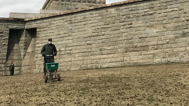 man with fertilizer in front of statue of liberty