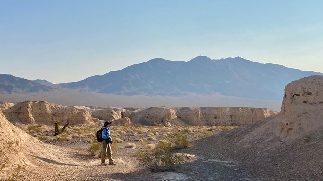A hiker within desert badlands.