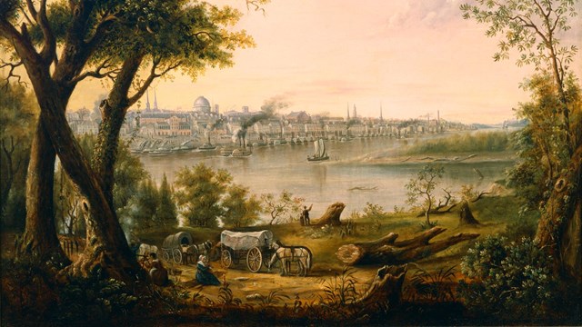 Buildings and the Mississippi River in the background with people walking in woods in the foreground