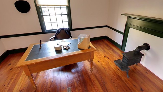 Farm office including a light colored wood desk and a small cast iron stove