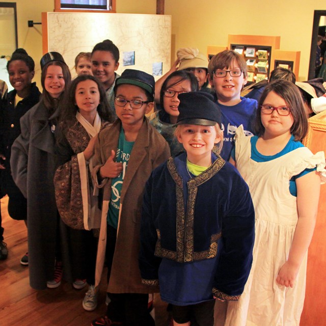 children dressed up in 19th century clothing in a museum exhibit.