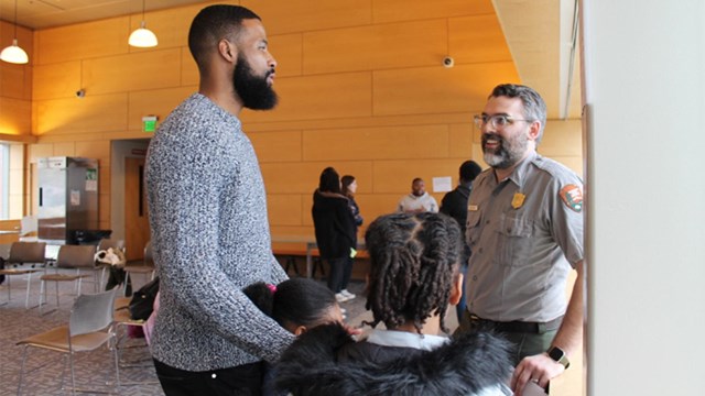 Image of a family talking to a Park Ranger at an in-person program