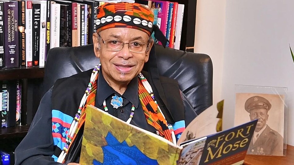 Middle aged man holding a story book and smiling at the camera.