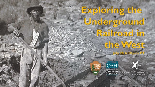 Black man in work clothes holds shovel and stands next to stream, mining for gold 