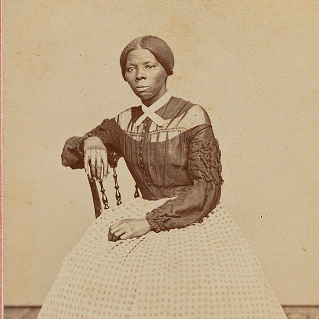 A young Harriet Tubman sits in a chair turned at an angle from the camera.