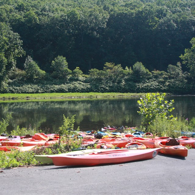 empty red kayaks laying on the edge of a river