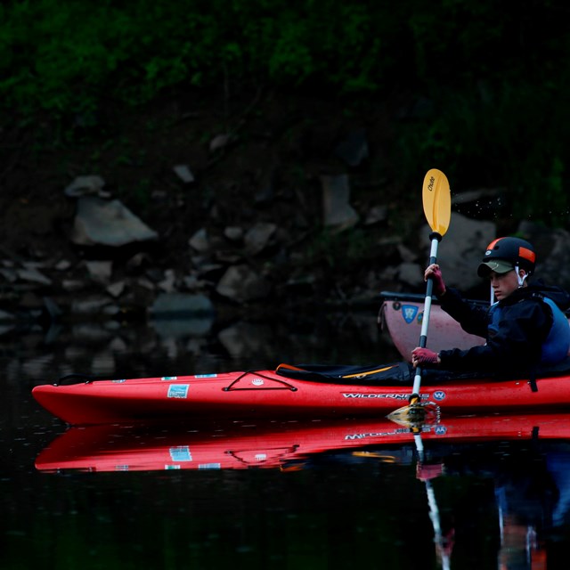Young boy in kayak cuts through the water.