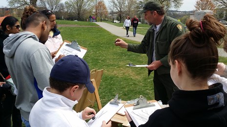 Park ranger speaks to a group of children and some adults holding clipboards