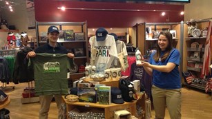 Bookstore employees holding up Find Your Park merchandise. 
