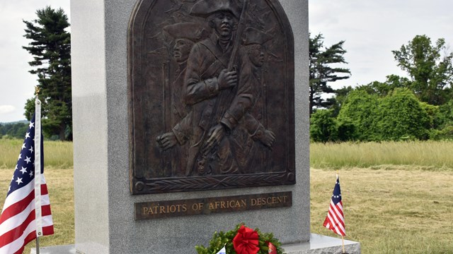 A stone monument with a bronze relief of three African American Continental Soldiers.