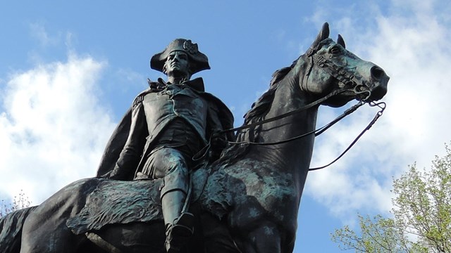 A bronze statue of a man on a horse sits atop a stone pedestal.