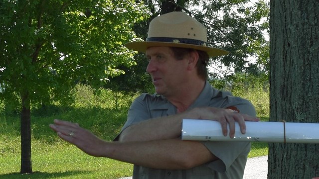 A ranger points in two directions, crossing his arms.