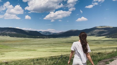Woman looking at expansive landscape with distant mountains