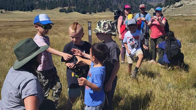 A park ranger shows students a piece of obsidian while hiking the La Jara Trail.