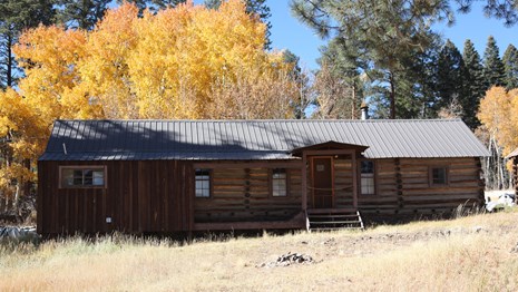 A log cabin in front of golden aspen trees.